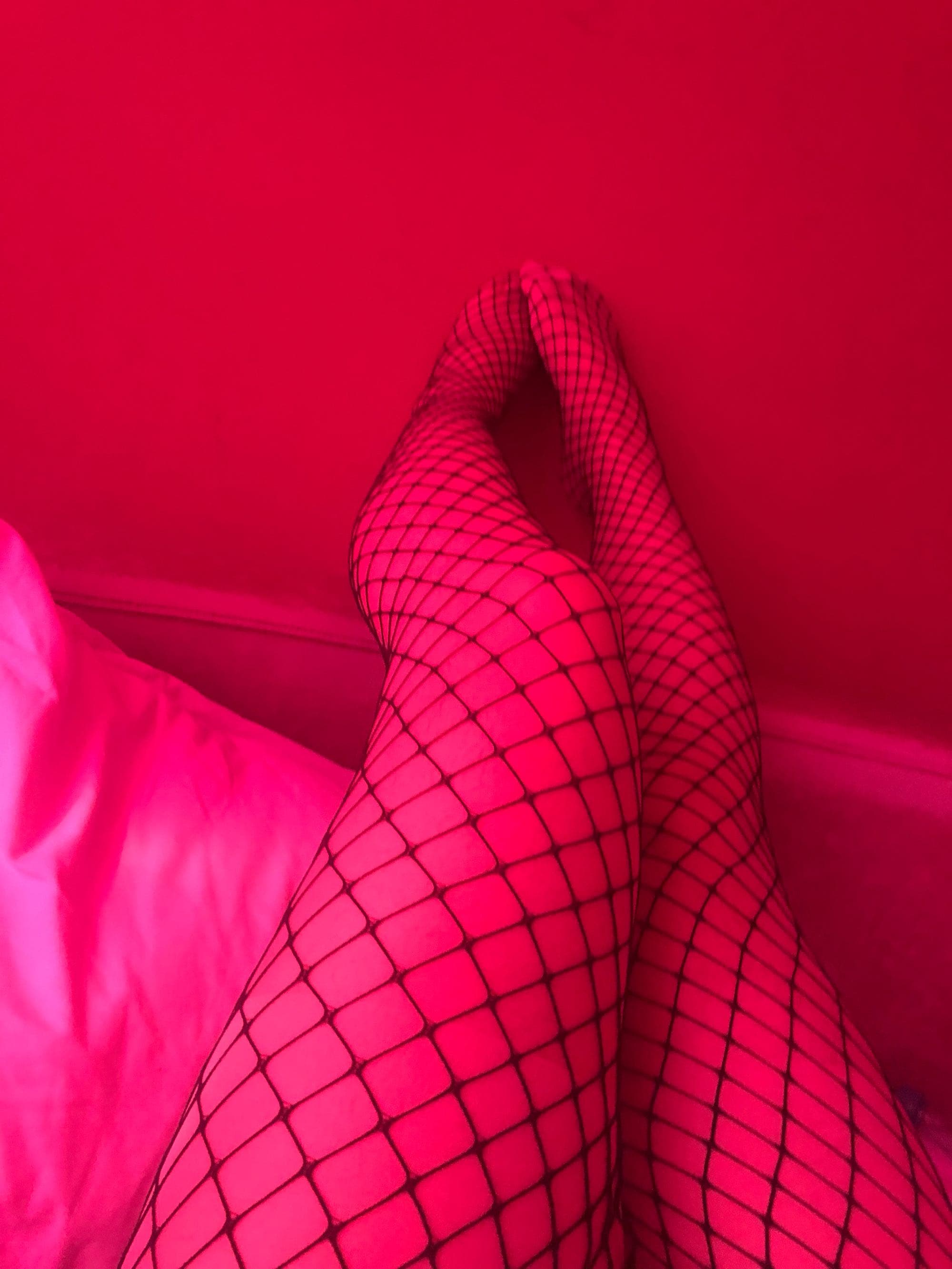 Feet encased in black fishnet stockings, diamond pattern hugging toes and arch under soft light