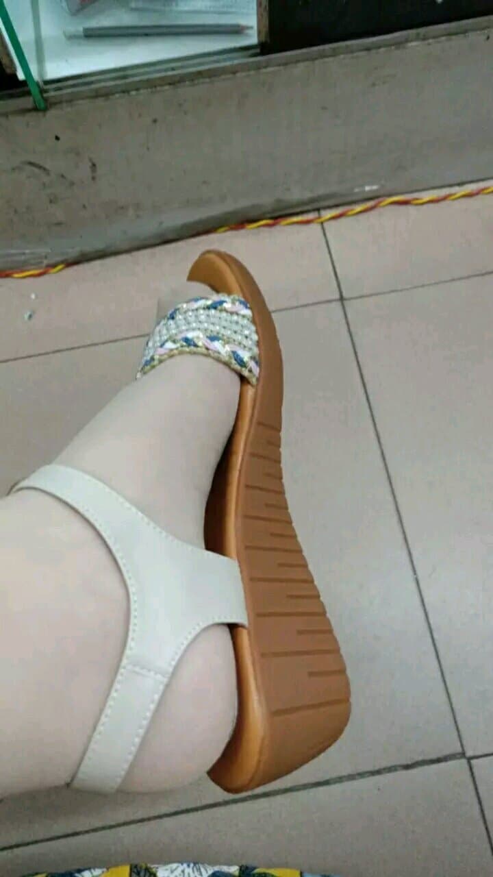 Sandal-clad foot with short stocking edges visible, toes painted and straps hugging the ankle under warm sunlight.