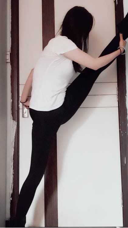 Ballet student in class, pointed toes in sheer tights, ribbons around ankles in soft studio light