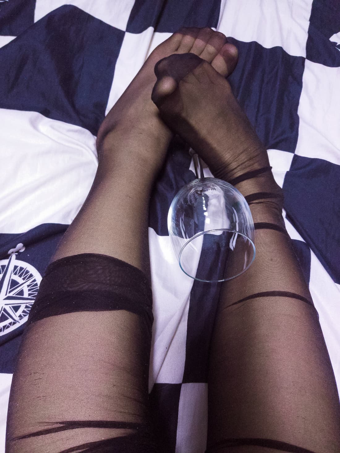 Bare feet resting on a plush blanket with silk stockings gathered around delicate ankles