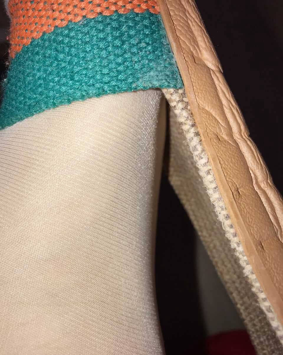 Two slipper-clad feet entwined on a plush rug, one bare heel peeking from a cotton sock