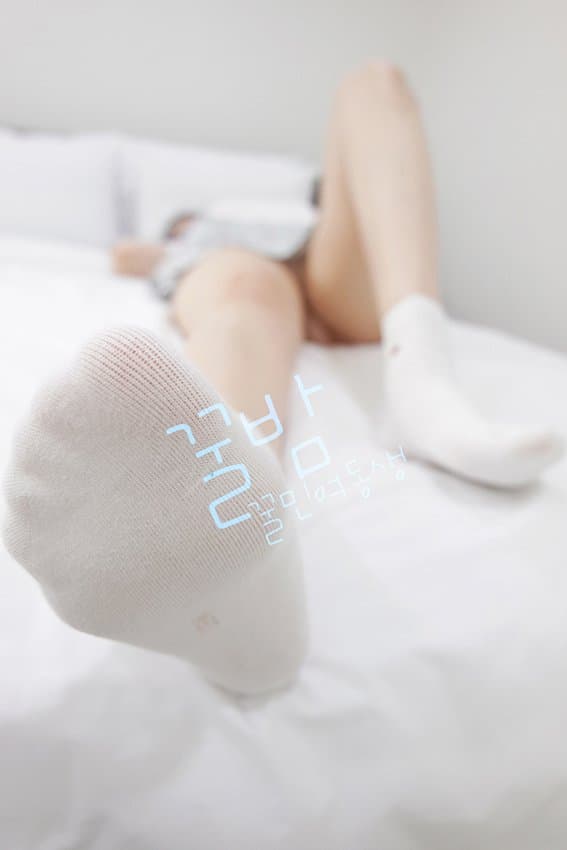 Garter belt and lace underwear framing thigh-high socks, legs crossed to reveal glossy nylon and a bare ankle.