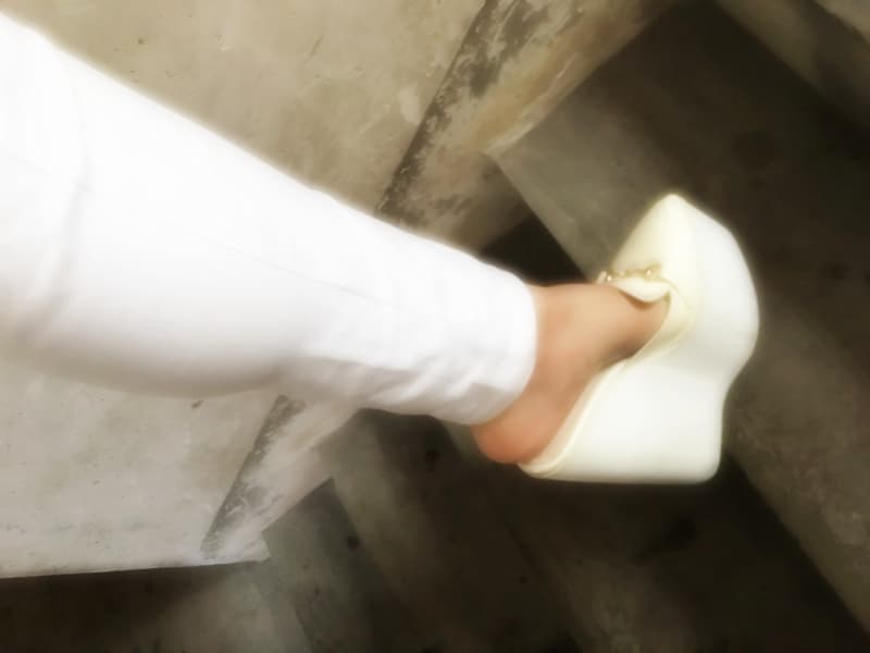 Bare Asian feet with rolled-down sheer stockings resting on a satin surface under warm, moody lighting.