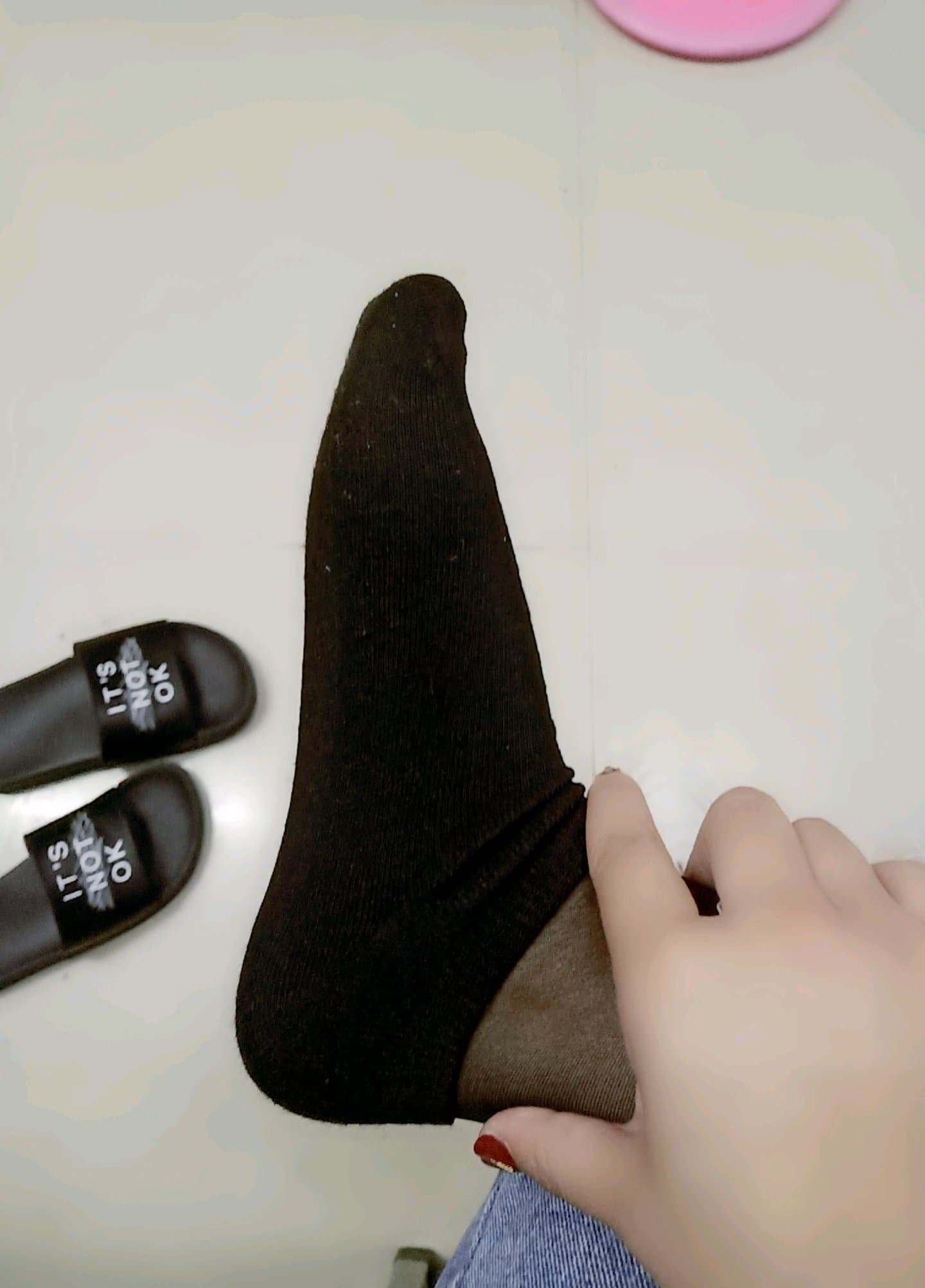 Girl lounging with socks on, soles hidden, ankles crossed, lazy allure and slightly worn fabric visible.