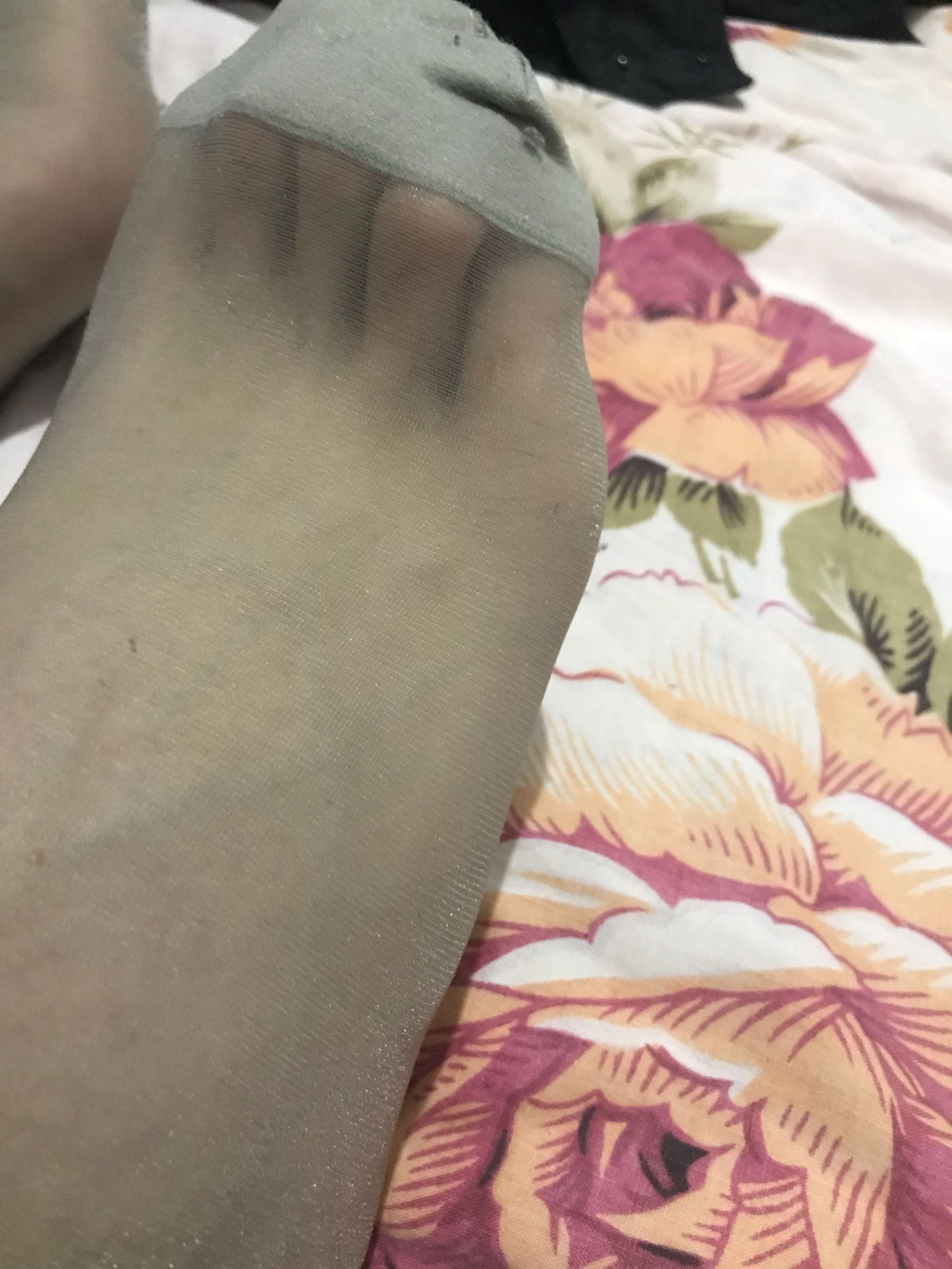 Close-up of ankles in short silk stockings, sheer nylon hugging toes and soft skin in warm, intimate light.