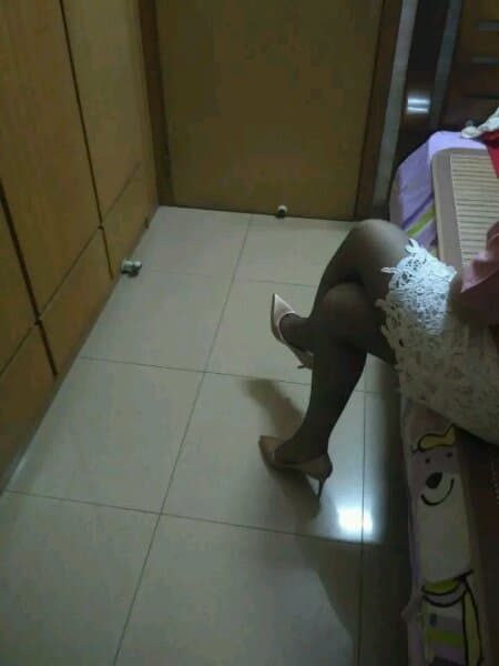 Stockings-draped leg on a couch, toes flexed toward the camera with intimate dim lighting setting a private mood.