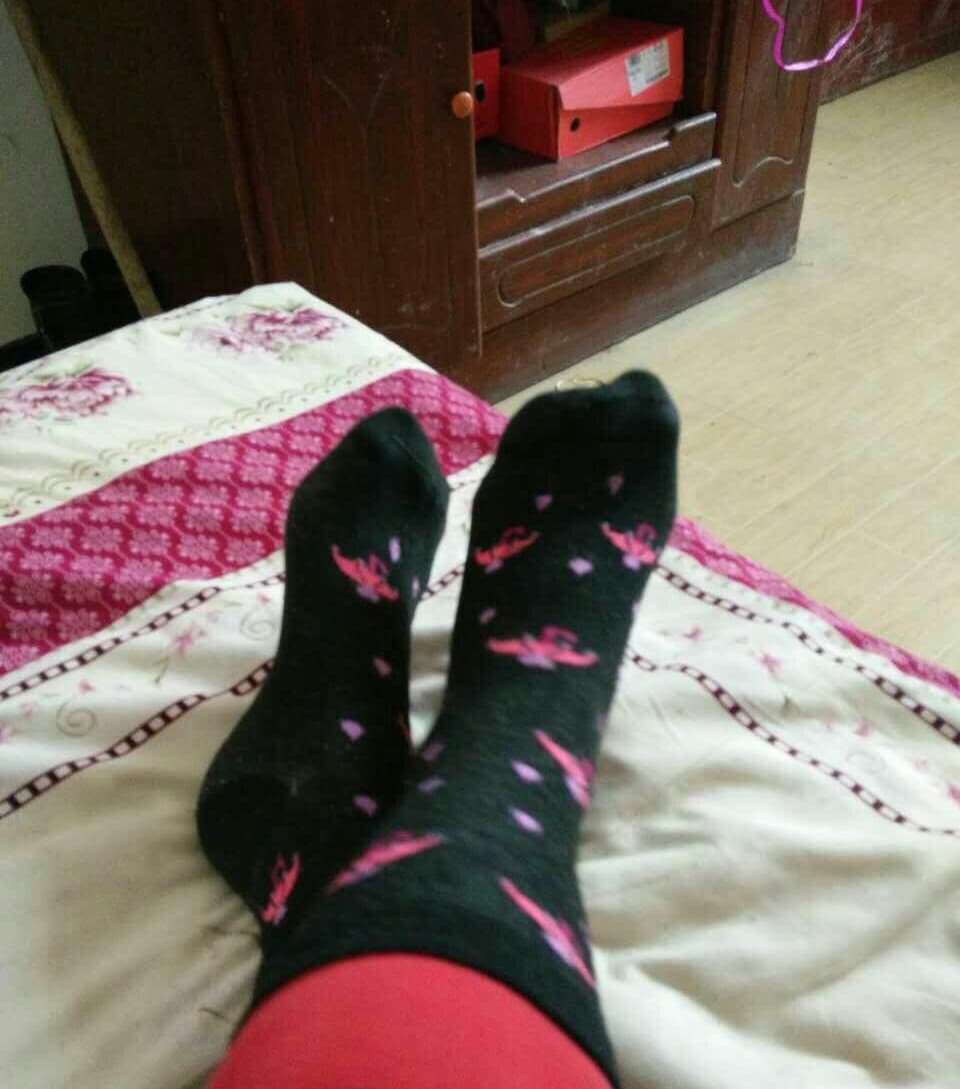 Worn thick cotton socks hugging a relaxed foot, textured fabric showing gentle wear and creased heels under soft light.