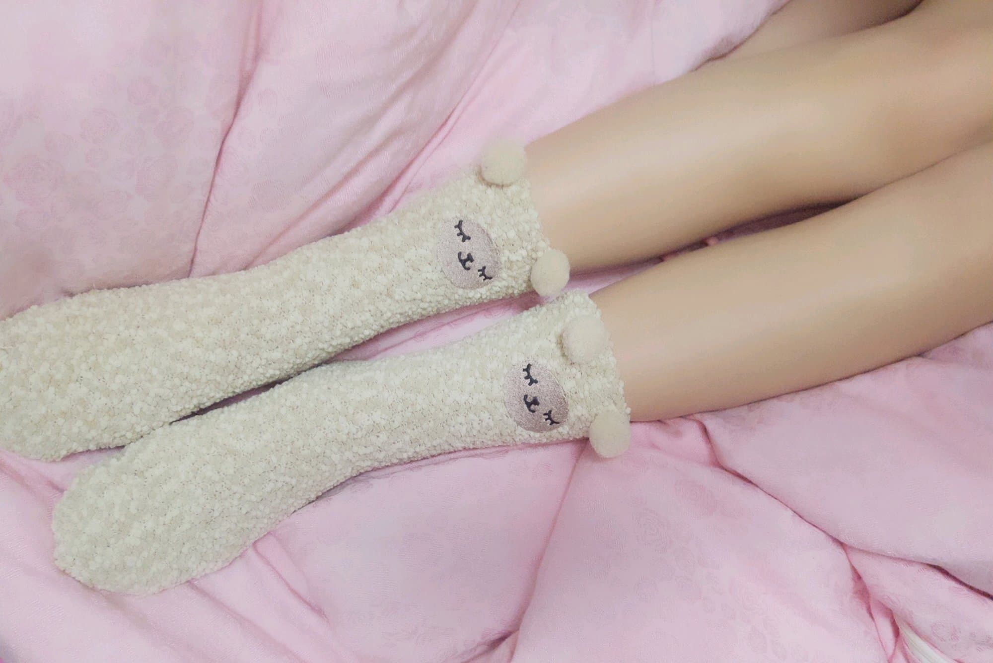 Warm indoor scene of cozy cotton socks and bare feet curled under a soft blanket