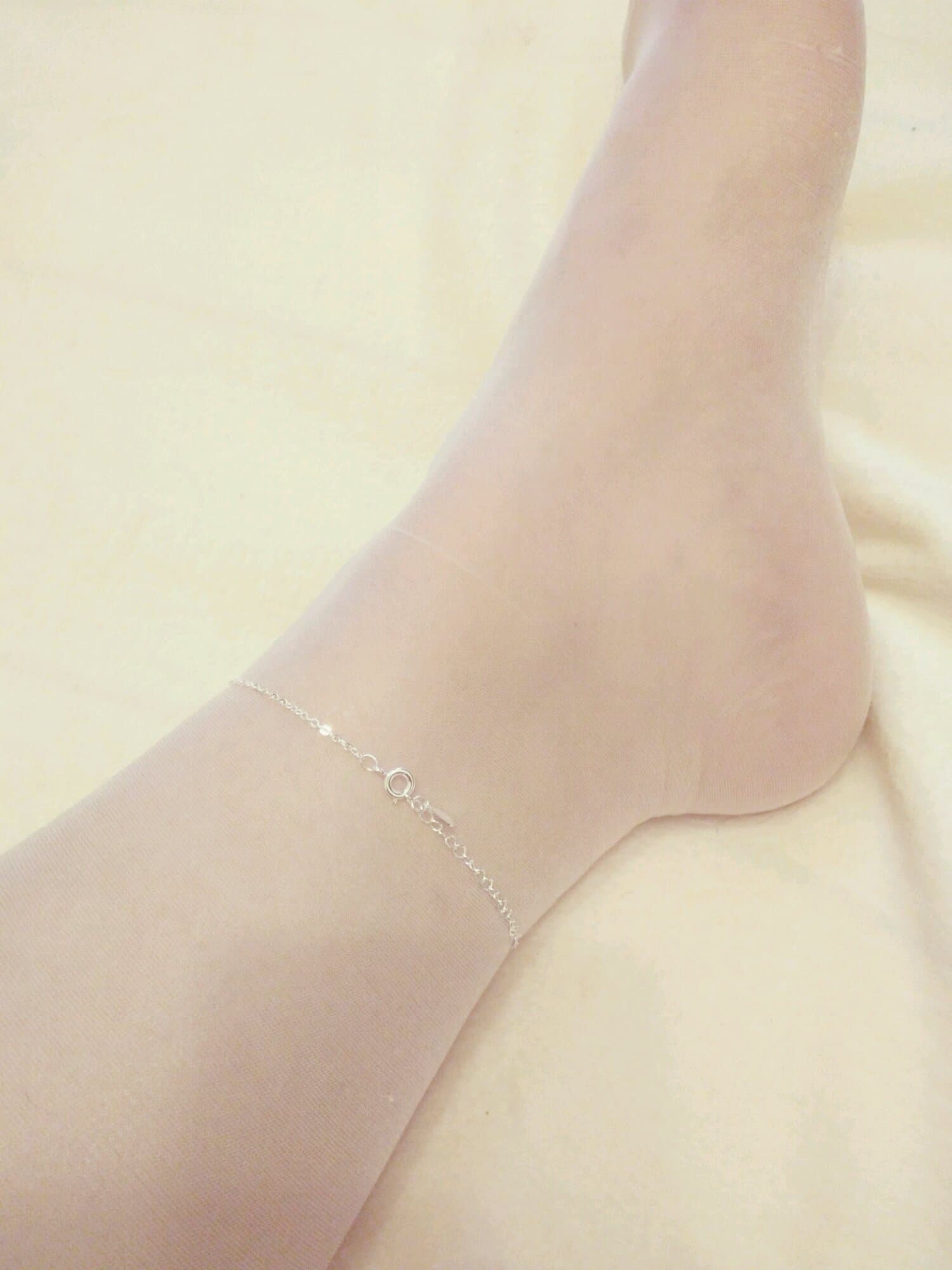 ankle chain resting on nylon stocking