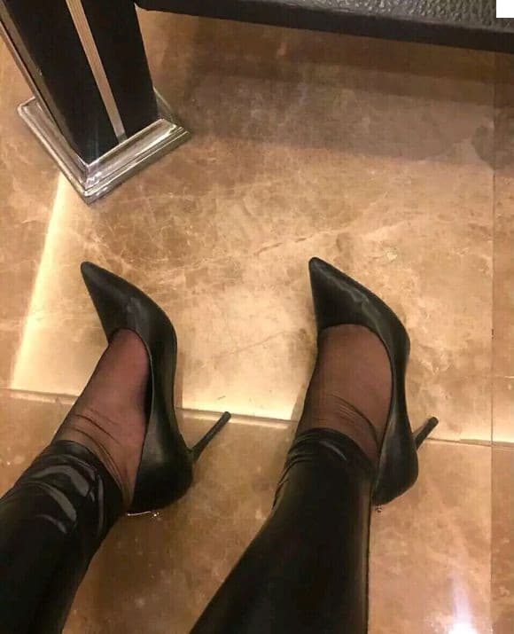 Feet in thin stockings and cozy socks curled together on a cool, textured floor