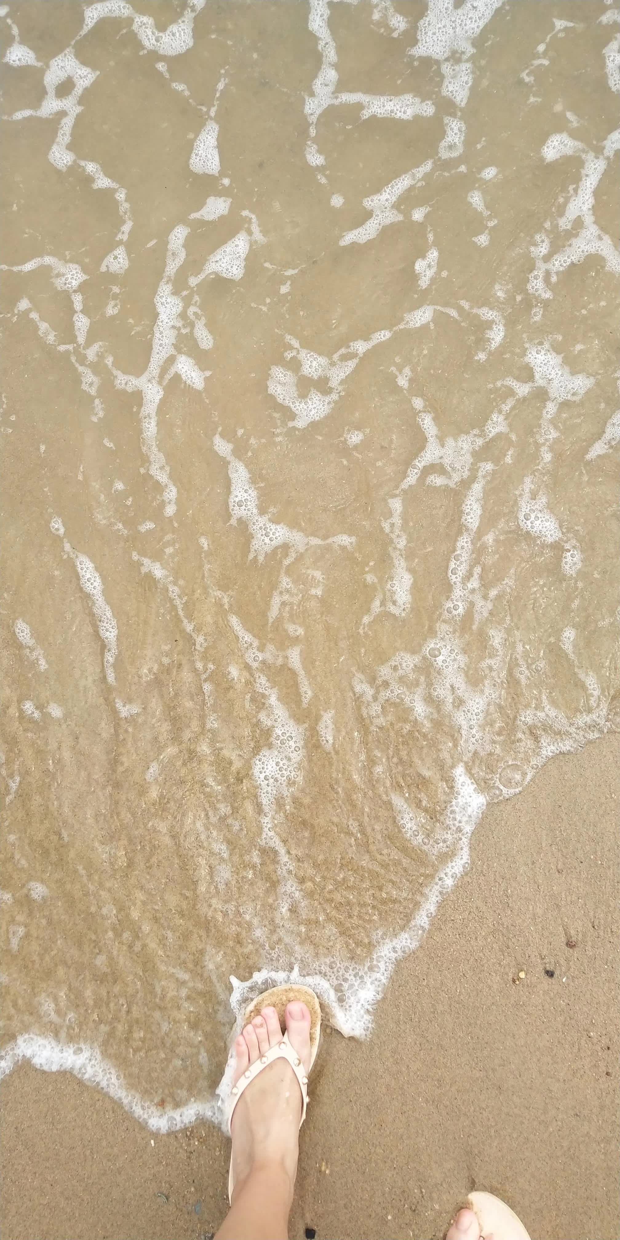 Close-up of bare Asian feet slowly slipping out of sheer stockings, toes curled on a warm wooden floor