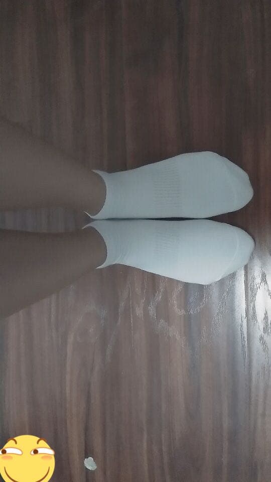 Low-light portrait of feet emerging from sheer nylons, stockings slightly wrinkled, intimate bedside composition