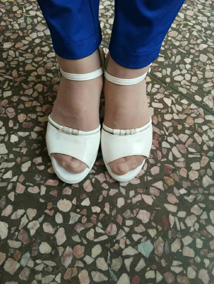 Sunlit close-up of sandal strap embracing a bare foot, toes curled with a gentle glossy highlight on the skin.