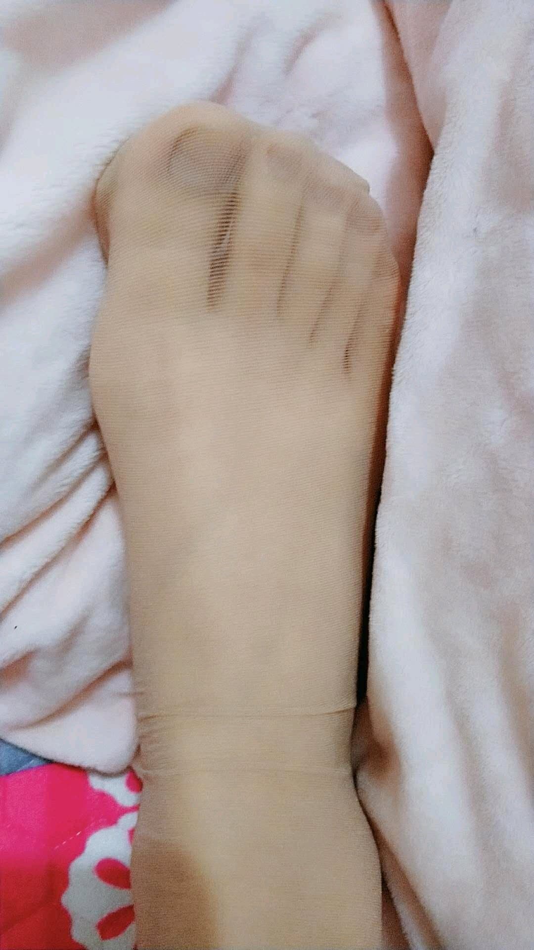 Close up of bare feet slipping from black nylon stockings