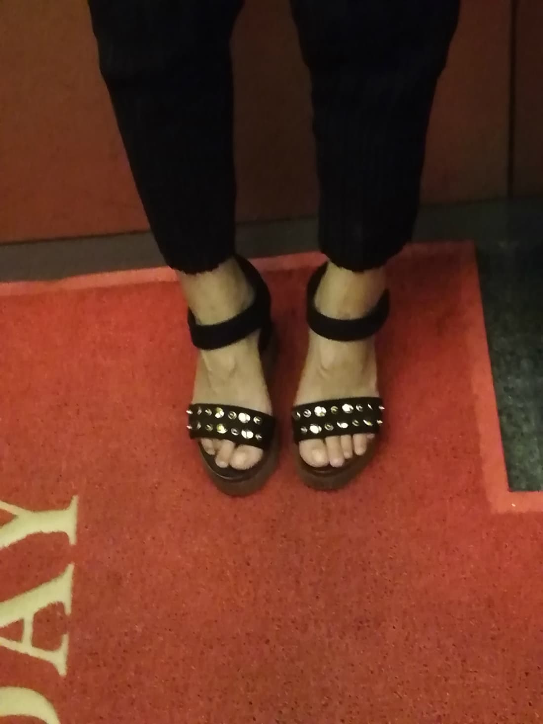 View of feet in sheer stockings in a dim elevator, toes pointed delicately toward the shiny metal doors