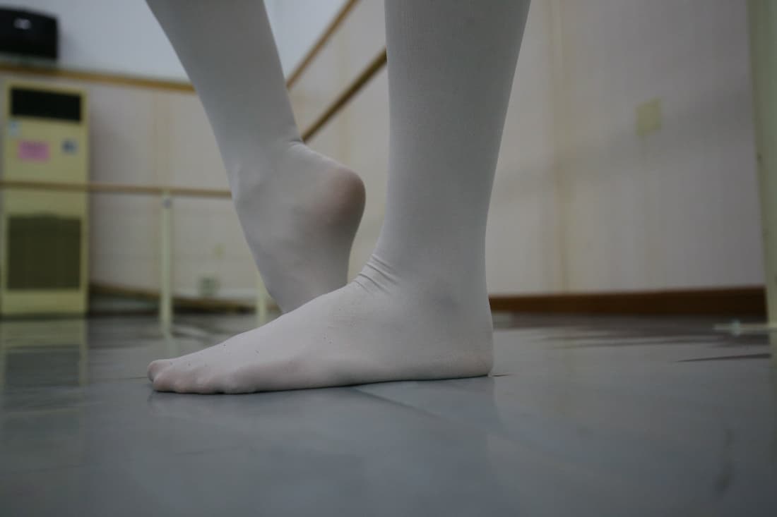 Adult dance instructor in sheer stockings arching her foot gracefully during a studio routine