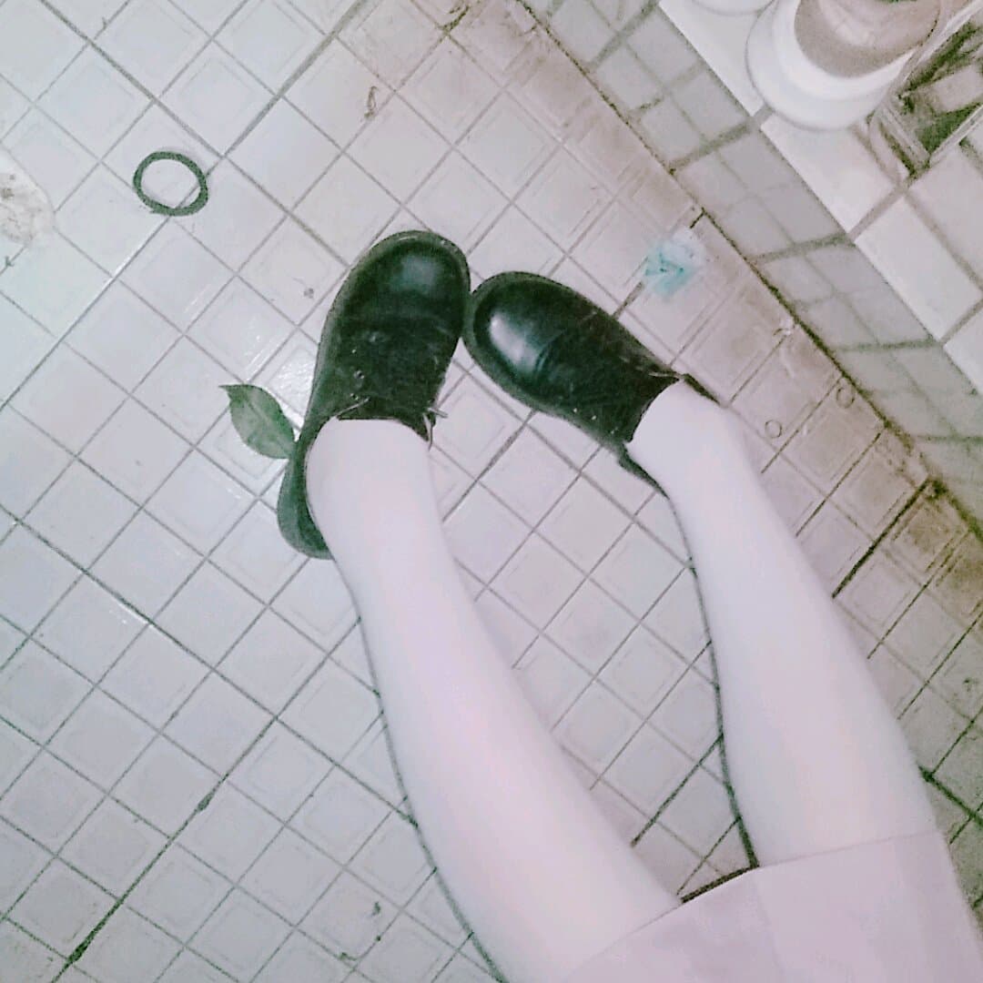 Wet nylon-clad feet with glistening toes peeking from soaked stockings on rain-slick pavement