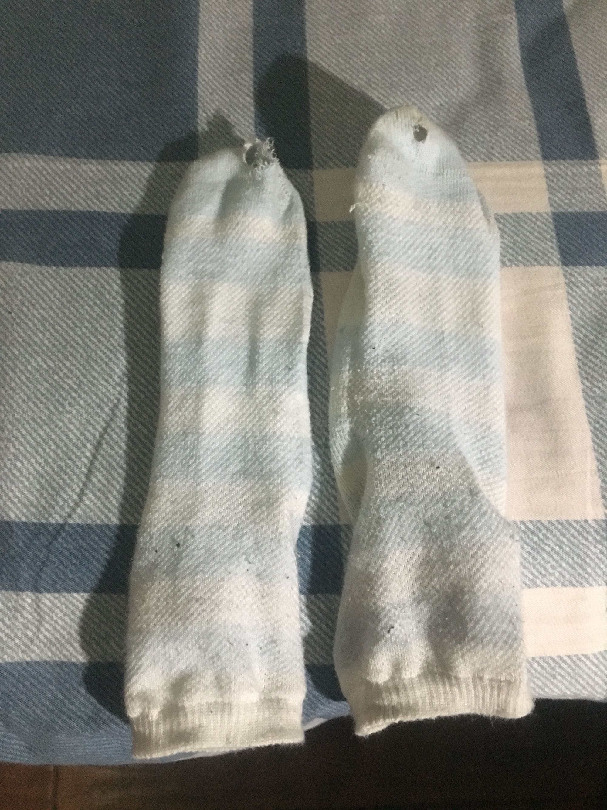Pile of well-worn socks folded on a chair showing gentle stretching, soft pilling, and intimate texture