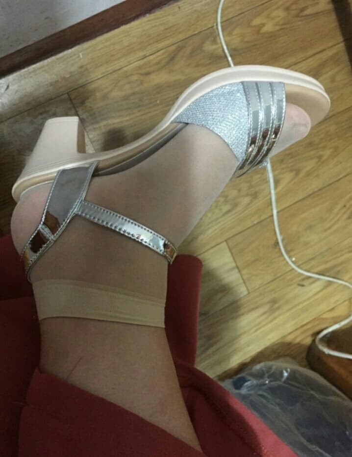 Close-up of feet in delicate sandals showing toes, straps, and sunlit skin with a sensual curve