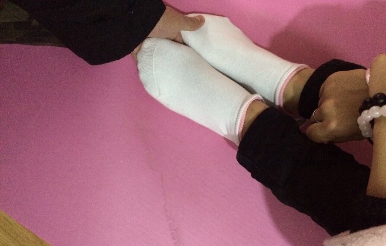 Yoga practitioner stretching, soles exposed and toes flexed against a mat