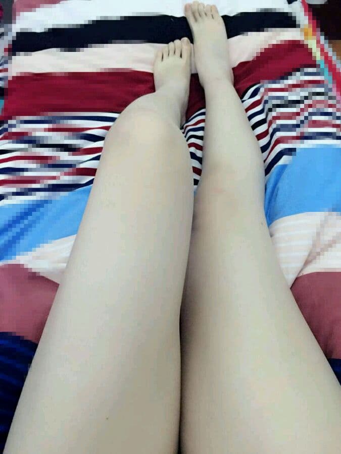 Bare feet on hardwood floor, toes slightly splayed and faint sock lines visible, intimate nighttime ambiance.