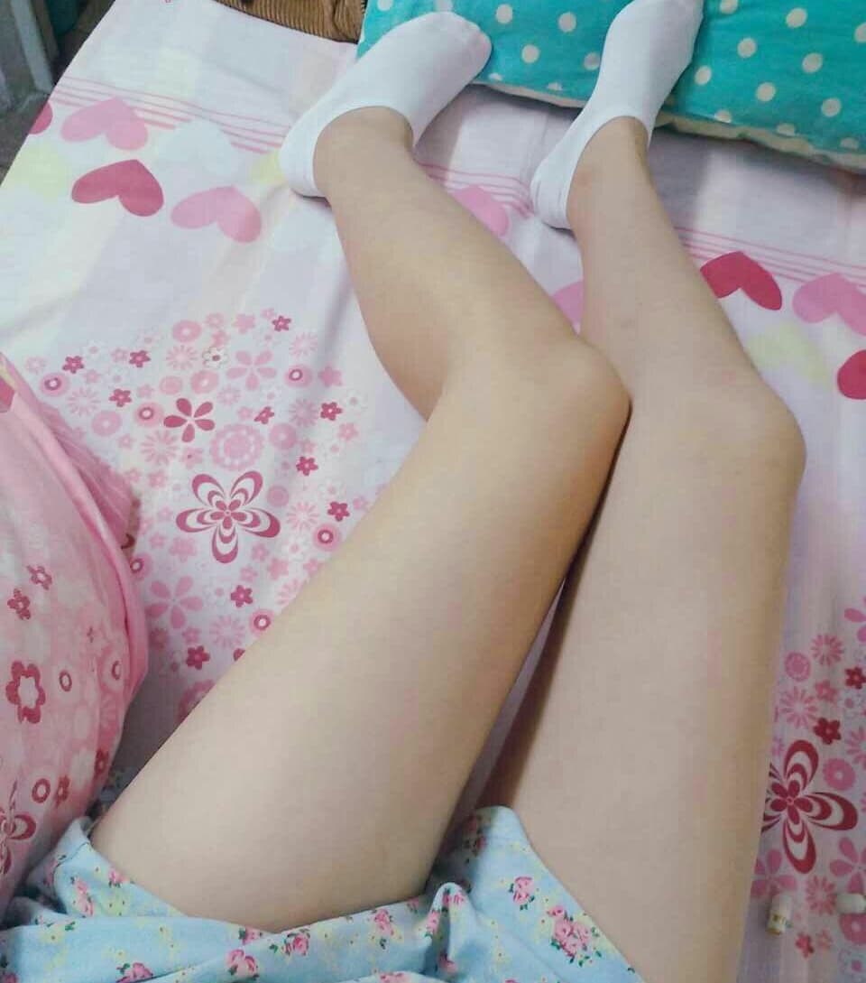 Close-up of a foot with wet-looking red nail polish, toes slightly curled on a silky sheet, soft lighting.