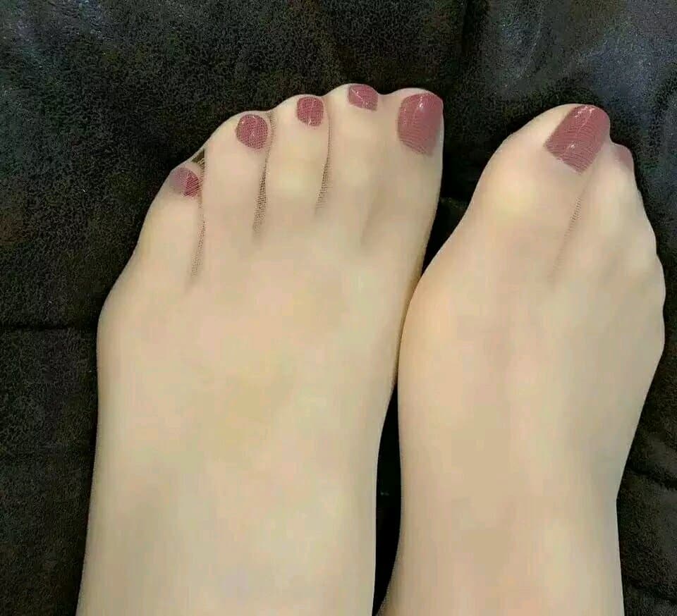 Two pairs of feet on a rug, one barefoot, one in thin socks, toes in playful proximity, warm lighting.