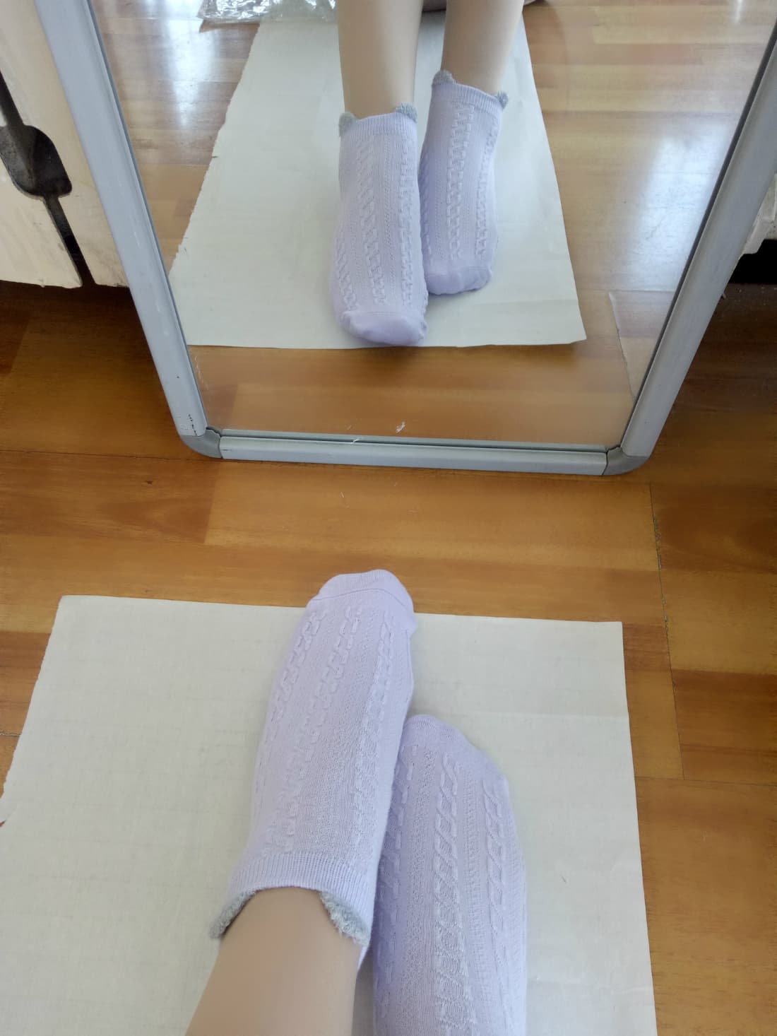 Two bare feet meeting, one slipping out of stockings, close focus on toe contact and arch alignment