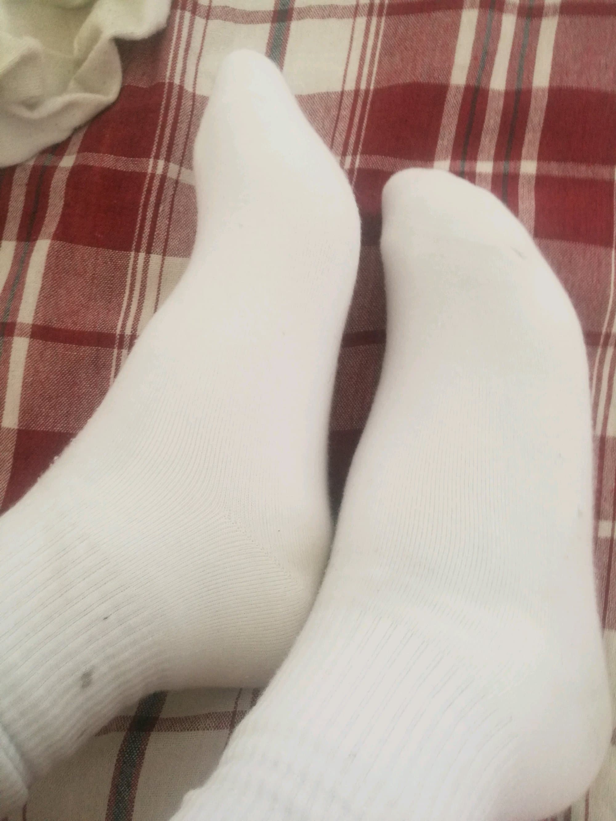 Pair of slightly discolored socks on a wooden floor, softened fabric and subtle sole impressions visible