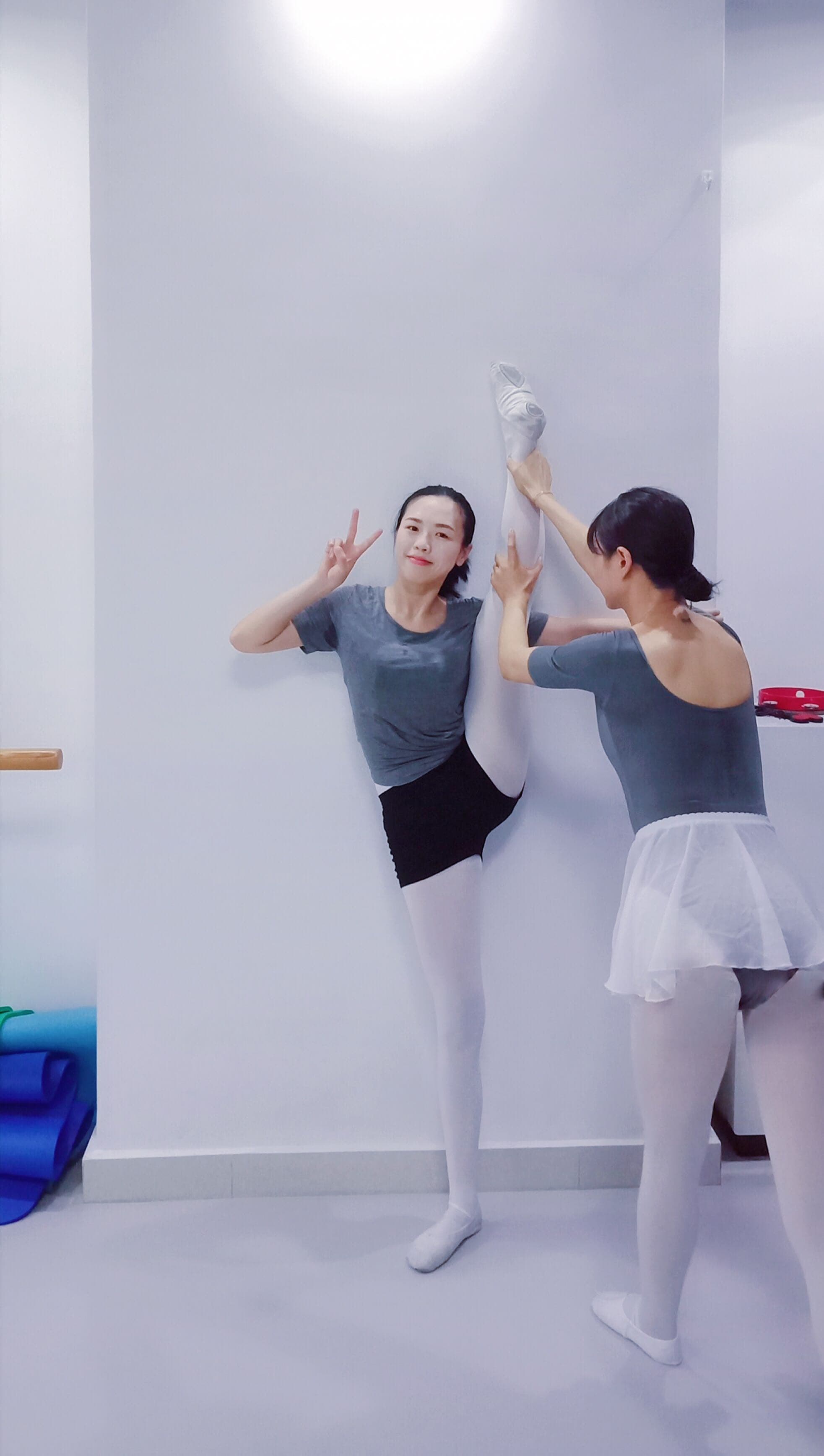 Adult dancer sitting in a studio, toe-shoe straps loosened, stockings and socks beside her on the floor