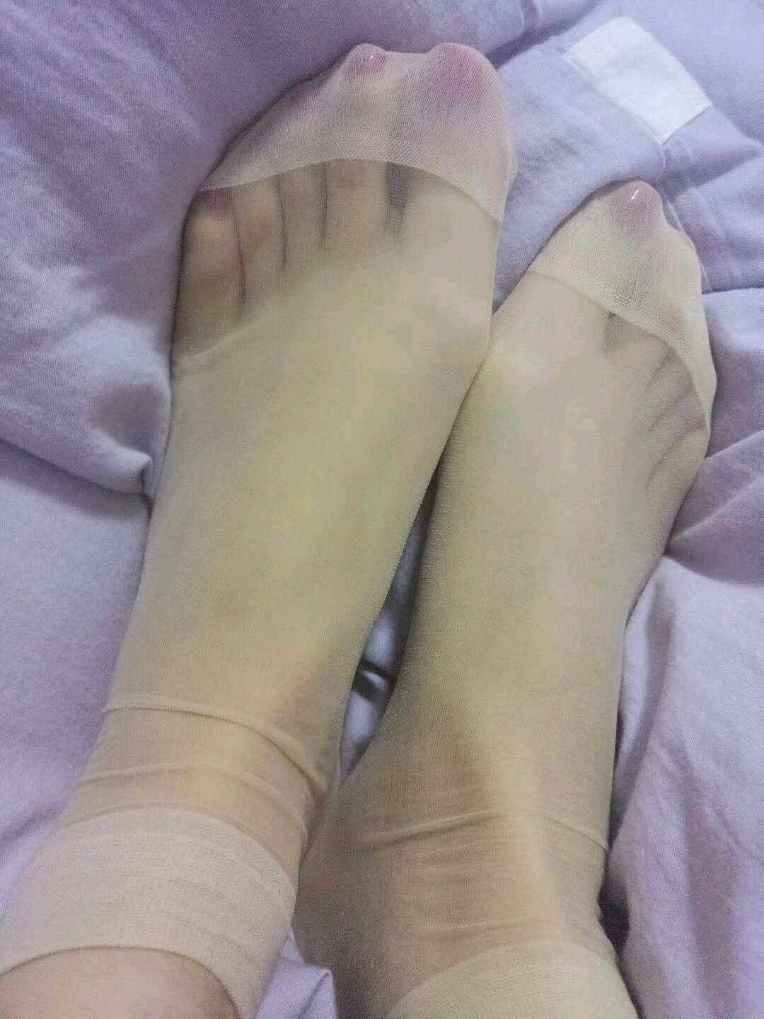 Close-up of a foot in low-cut boat sock and silk draped over the ankle, soft lighting