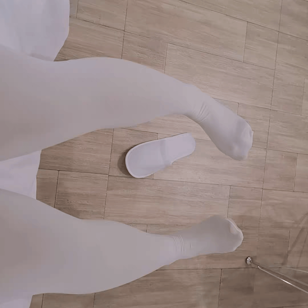 Artful close-up of nylon-clad ankle and foot, light catching the smooth surface of the pantyhose.