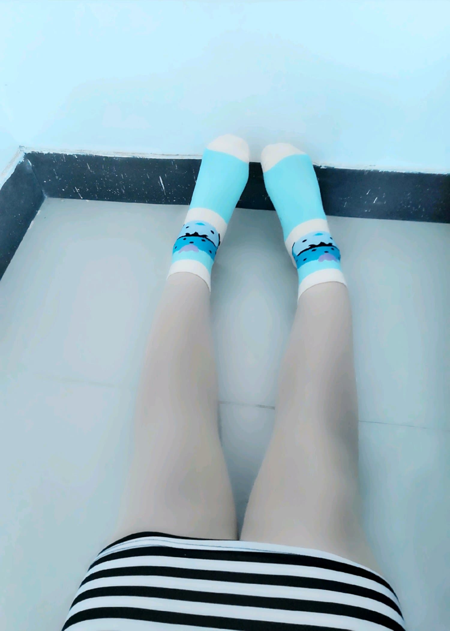 Feet clad in deep-colored nylons, one foot slightly lifted to show heel and arch, vivid hues contrasting with skin