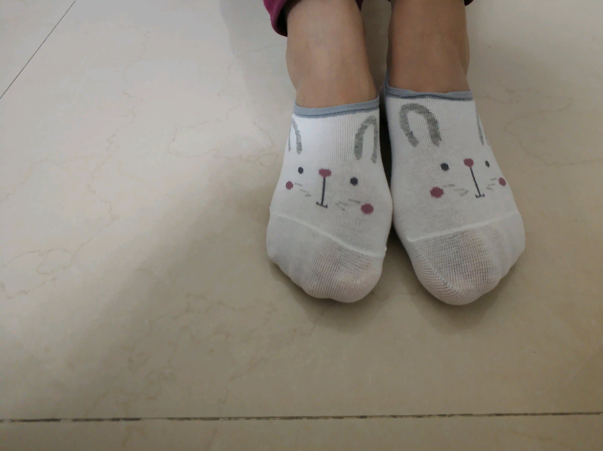 Feet bare on grass with sheer stockings rolled down, toes splayed playfully, sunlight highlighting skin and fabric textures