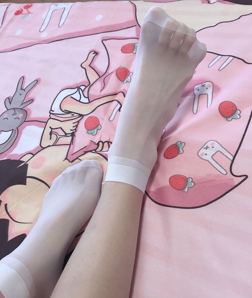 Short silk hem framing bare feet in sheer stockings, toes relaxed, natural light catching silky sheen and skin tones