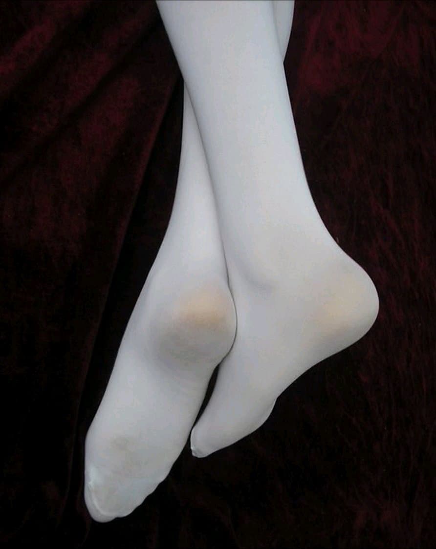 Sunlit backyard photo of stocking-clad ankles peeking from sandals, soft skin glistening with summer heat and nylon sheen.