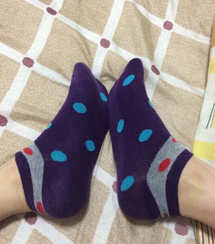 Close-up of small delicate female feet in low-cut boat socks, toes peeking, soft lighting creating intimate mood.