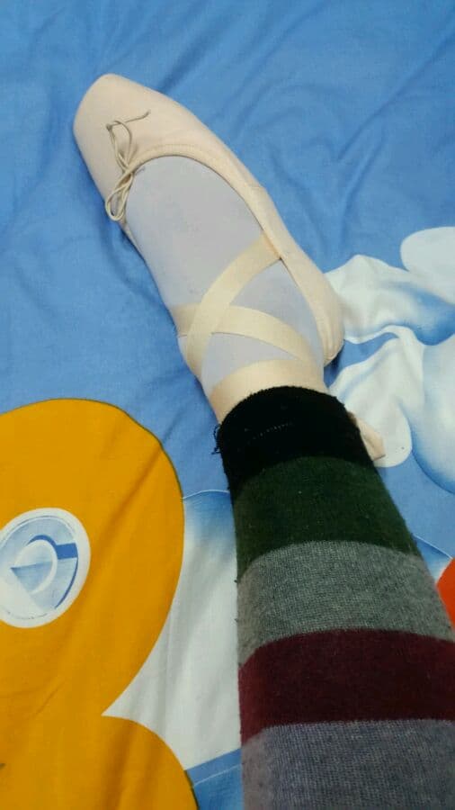 Legs extended in a leisurely stretch, nylon sheen highlighting the arch and toes lightly flexed against a plush surface.