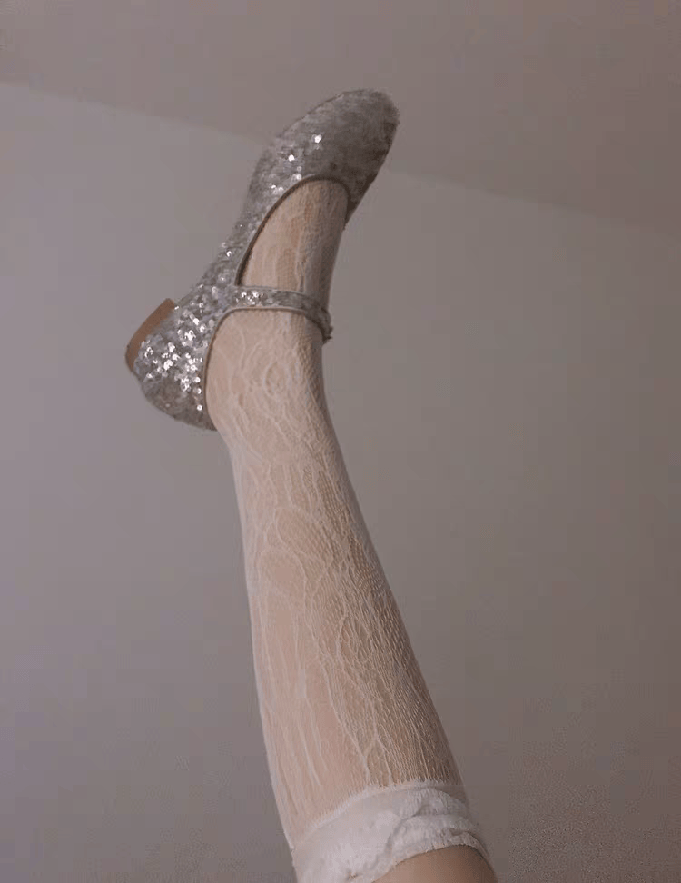 Worn cotton socks crumpled beside shoes, toes slightly visible and nylon shimmer nearby in soft home lighting