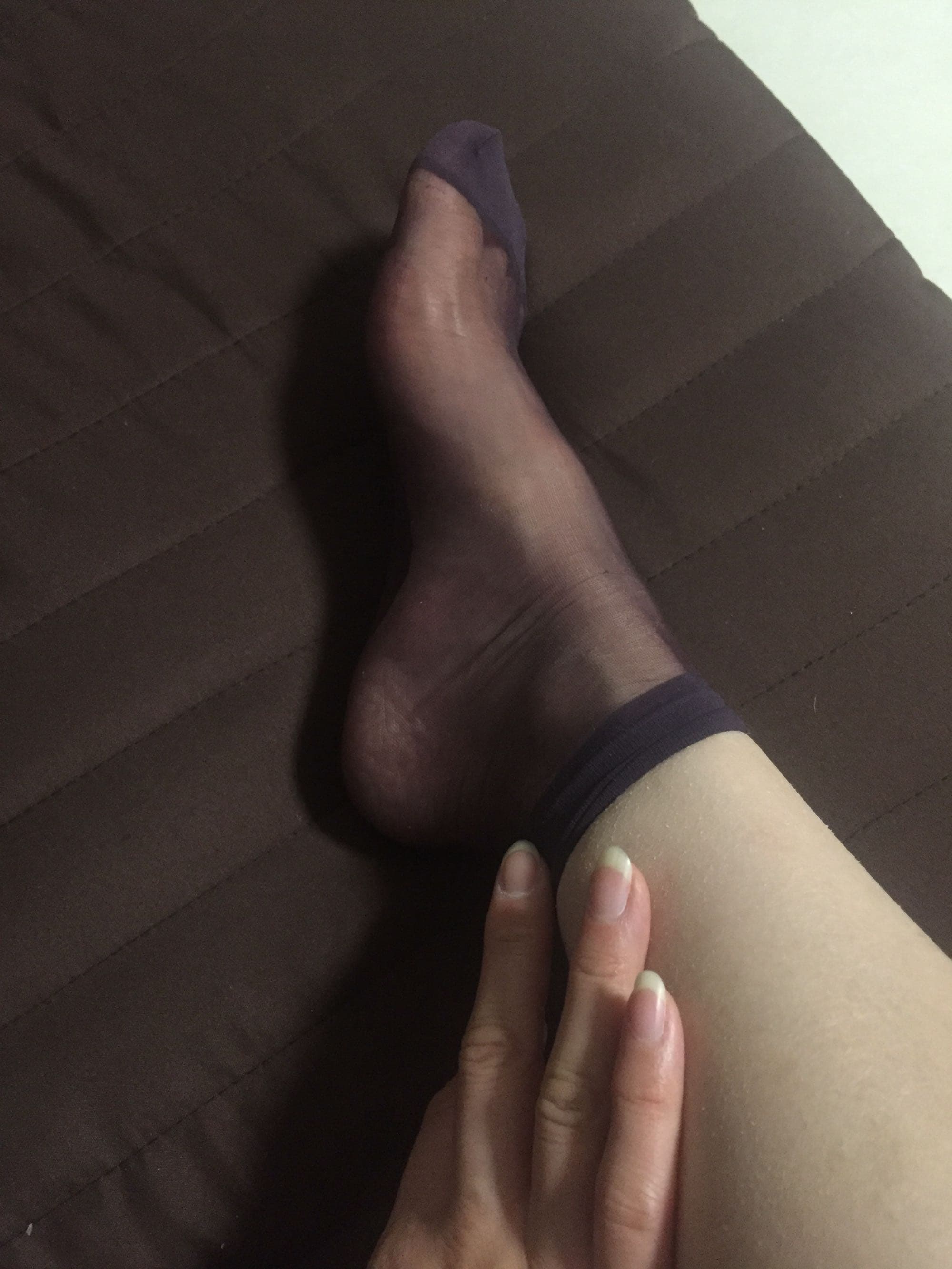 Ankle-focused shot of short sheer stockings with exposed heels and a hint of bare toe play on soft linen