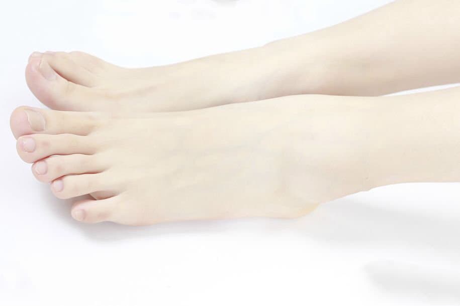 Adult woman in nostalgic attire accentuating her stockinged feet with a playful, mature expression