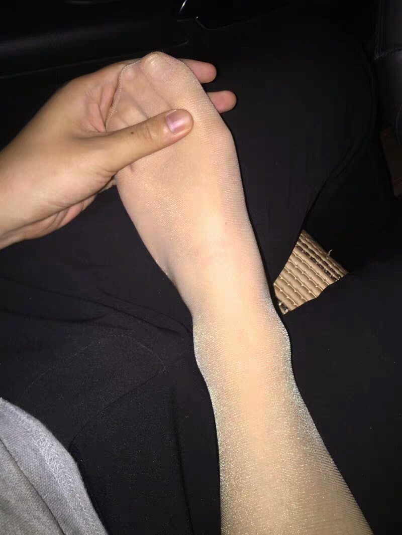 Close-up of a woman sliding into sheer nylon stockings, toes flexing against the fabric