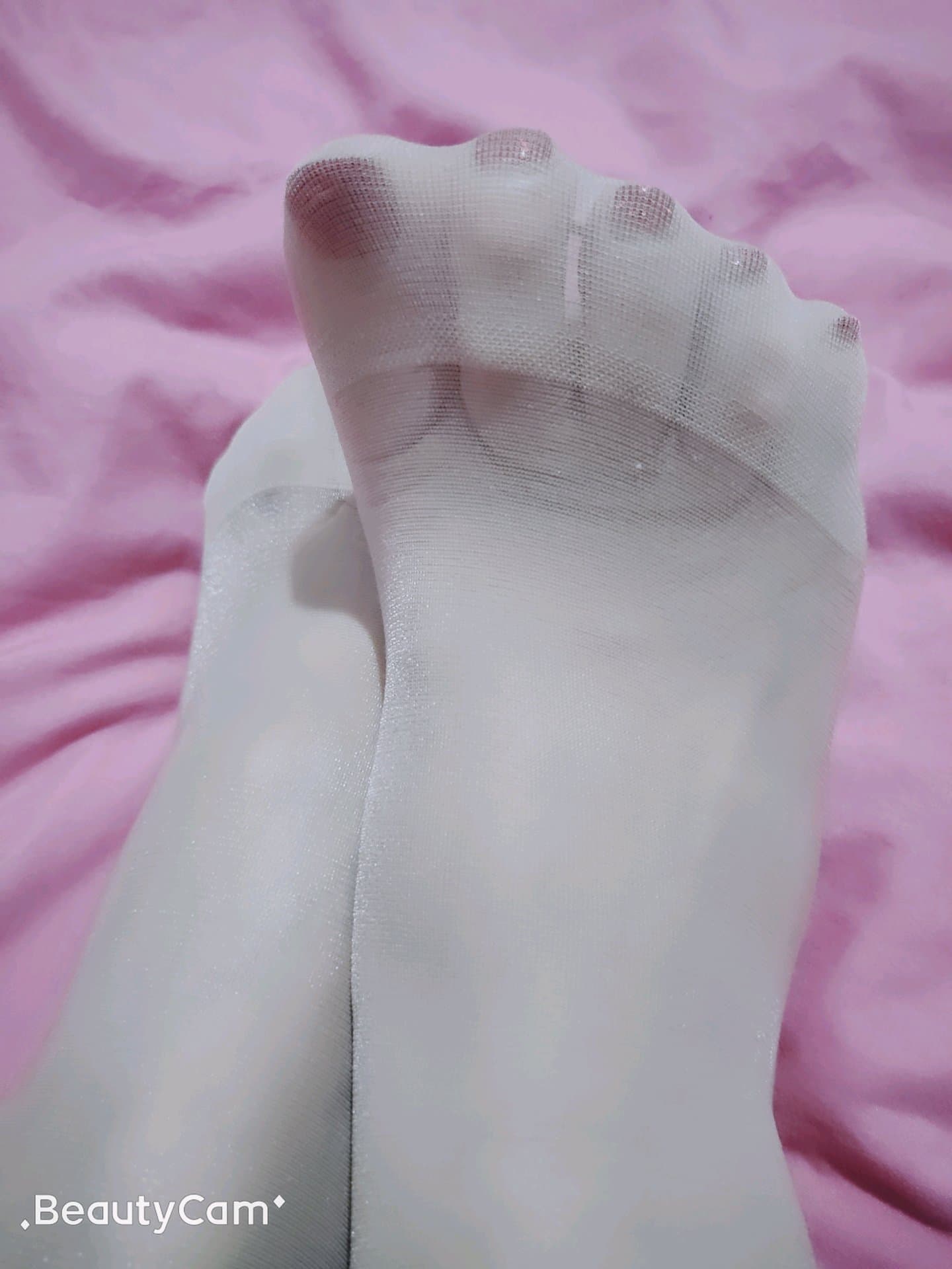 Pale stockings on slender legs, soft light accentuating arch and toes, lighter hues and glossy nylon texture