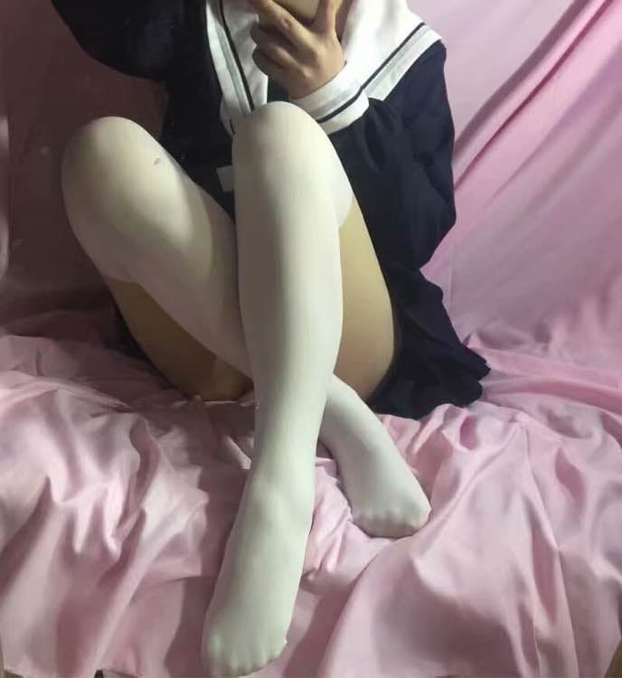 Adult in cat cosplay lounging, stockinged legs stretched out, toes visible through sheer nylon, playful pose