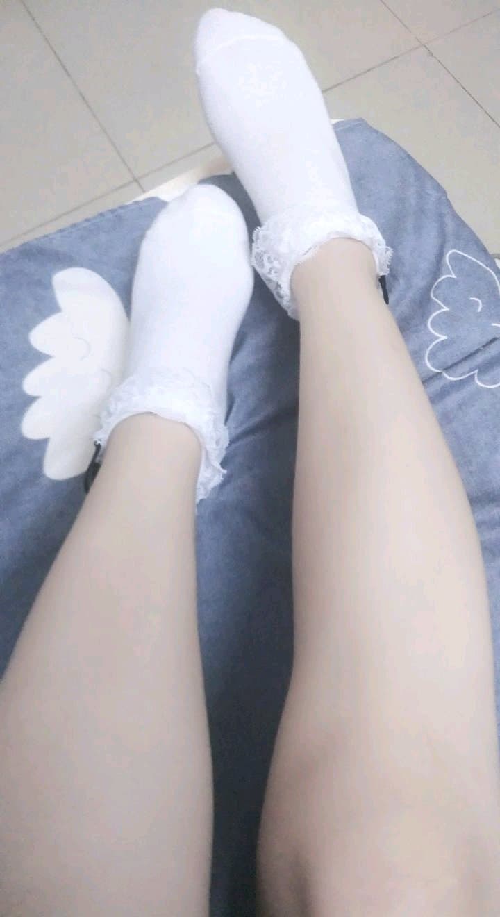 Close-up of bare Asian feet in sheer nylons, toes curled and stocking sheen catching the light, intimate mood