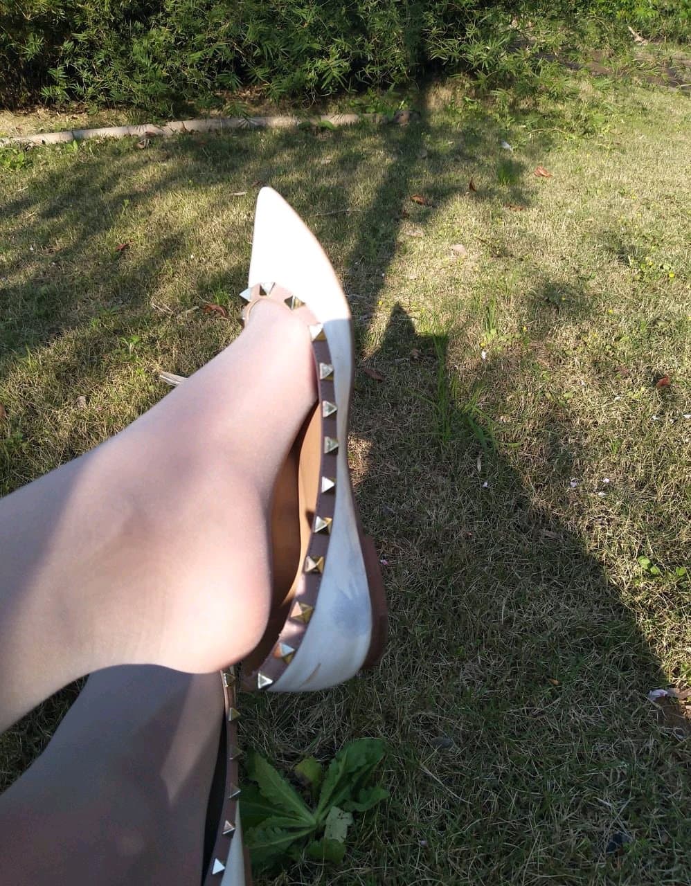 Sunlit reflective shot of sheer stockings and a bare toe peeking out, skin glowing in warm light