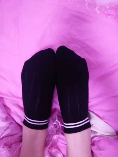 Large bare feet resting on rumpled sheets, toes slightly splayed, heel calluses visible, photographed with intimate, warm bedroom light.