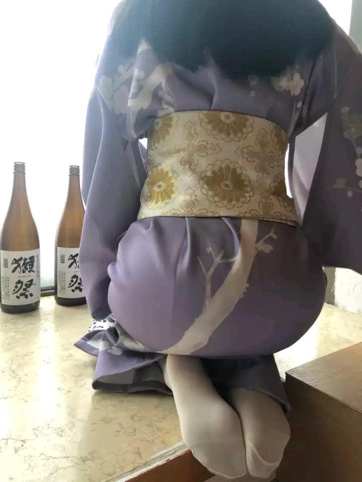 Guest on tatami mat slowly removing tabi-style socks, bare toes touching woven straw while traditional room light filters through shoji screens.