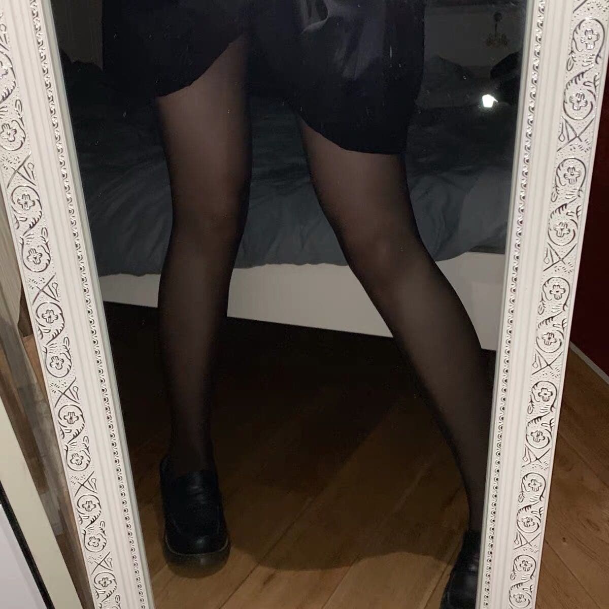 Portrait of feet in sheer stockings, toes slightly curled, held steady while eyes focus off-frame creating an intense, intimate atmosphere.