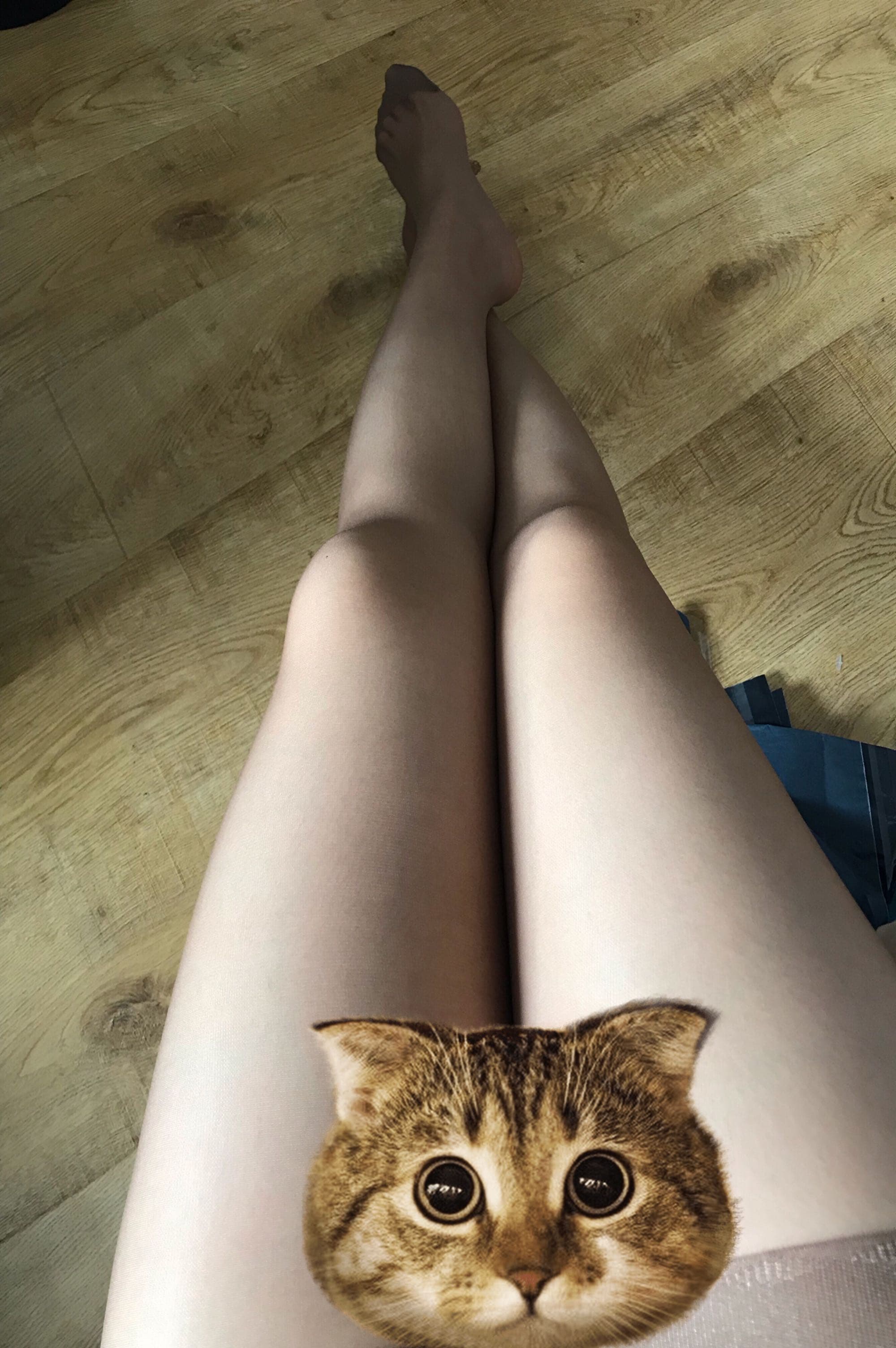 Woman under a desk flexing feet in sheer stockings, a small reveal of skin between shoe and hose.